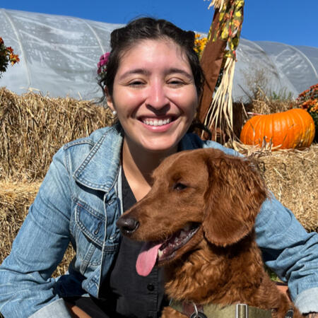 A picture of Kieran smiling and holding her dog, Remy.